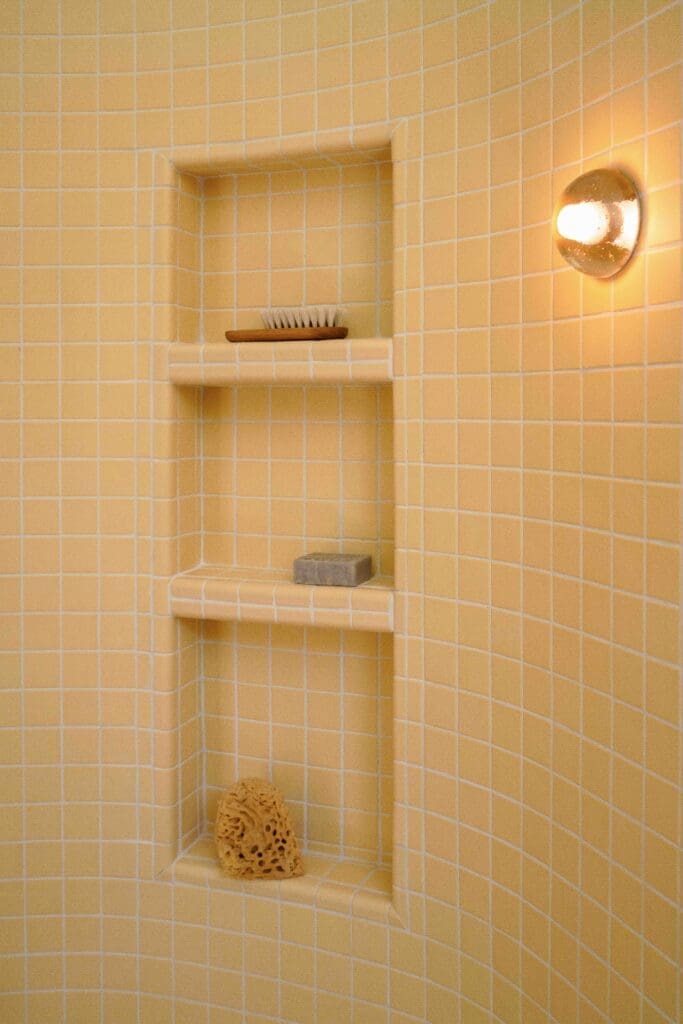 Curved walk-in shower with butter yellow tile in a mid-century modern Hollywood Hills bathroom renovation by The Warren.