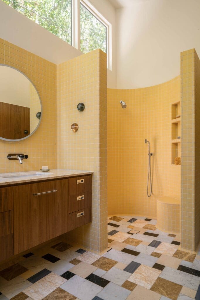 Curved walk-in shower with butter yellow tile in a mid-century modern Hollywood Hills bathroom renovation by The Warren.