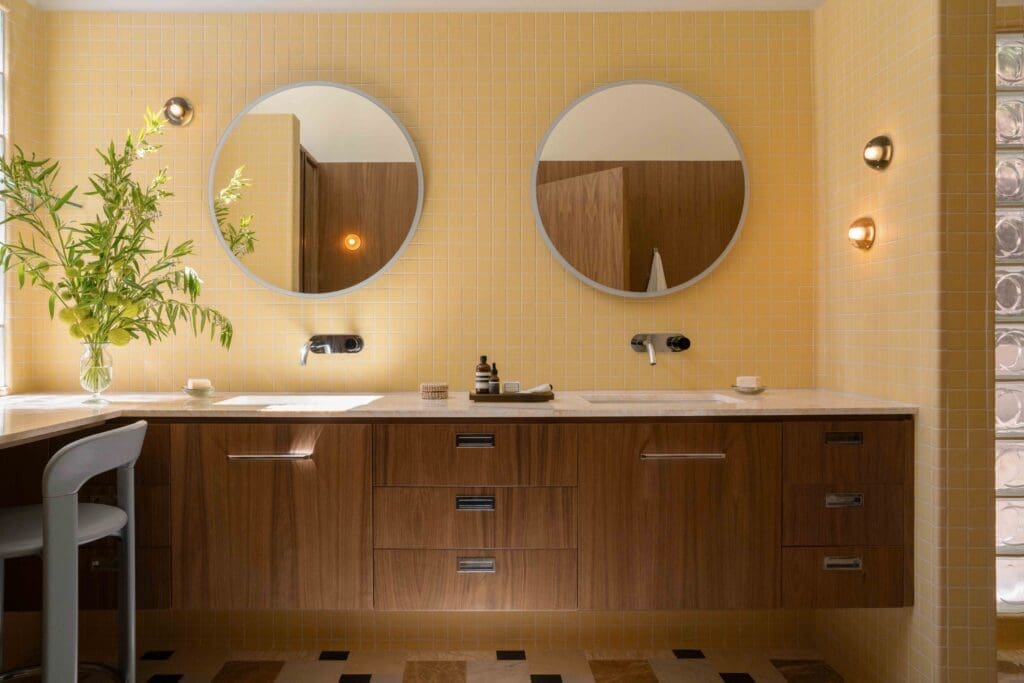 Custom walnut vanity with round mirror and domed sconces in a Hollywood Hills mid-century modern bathroom by The Warren.