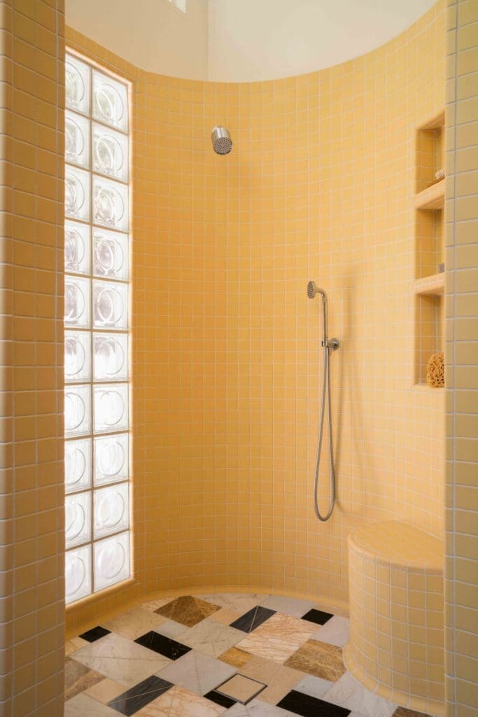 Glass block window with circular pattern beside the curved shower in a mid-century modern Hollywood Hills bathroom by The Warren.