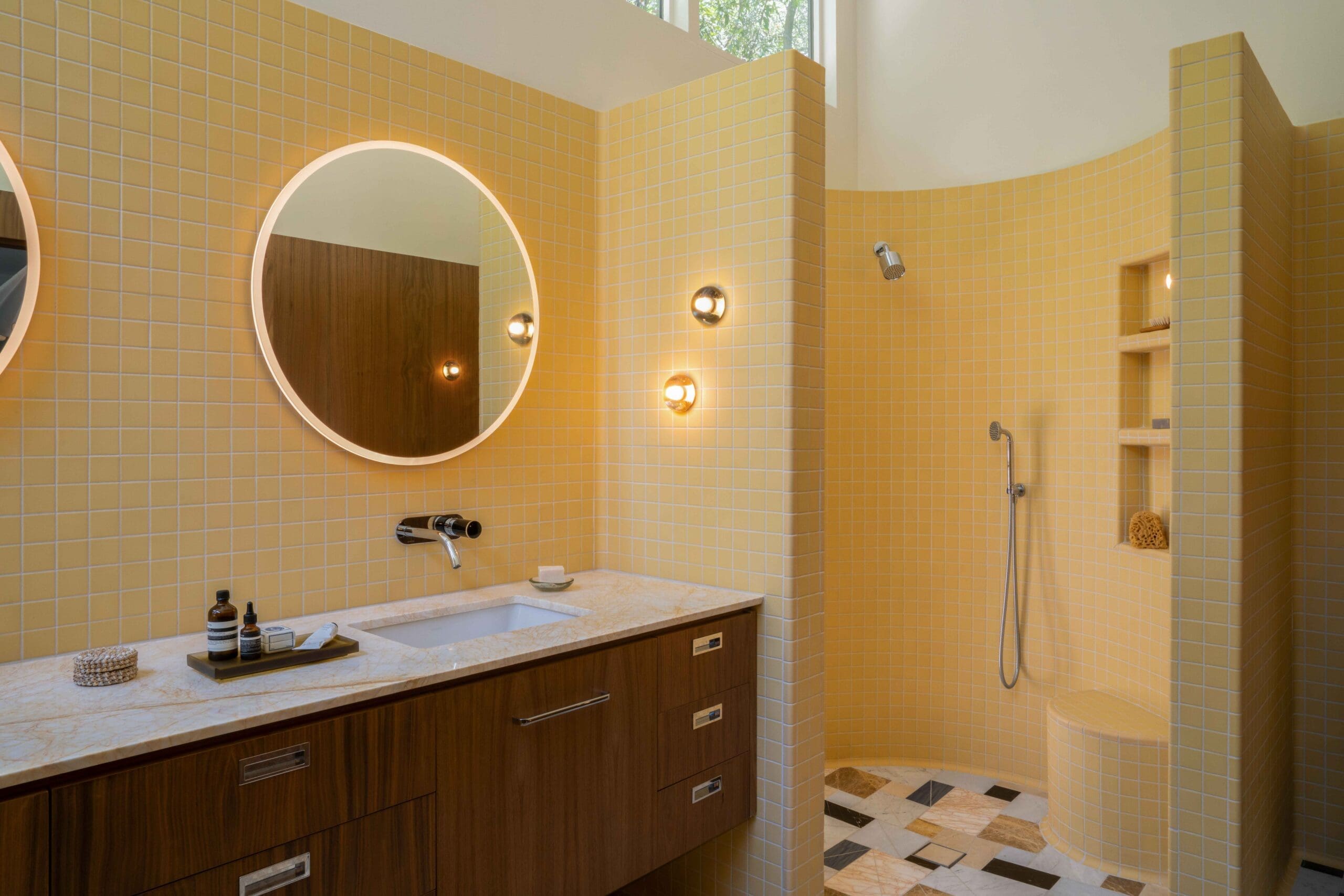 Curved walk-in shower with butter yellow tile in a mid-century modern Hollywood Hills bathroom renovation by The Warren.